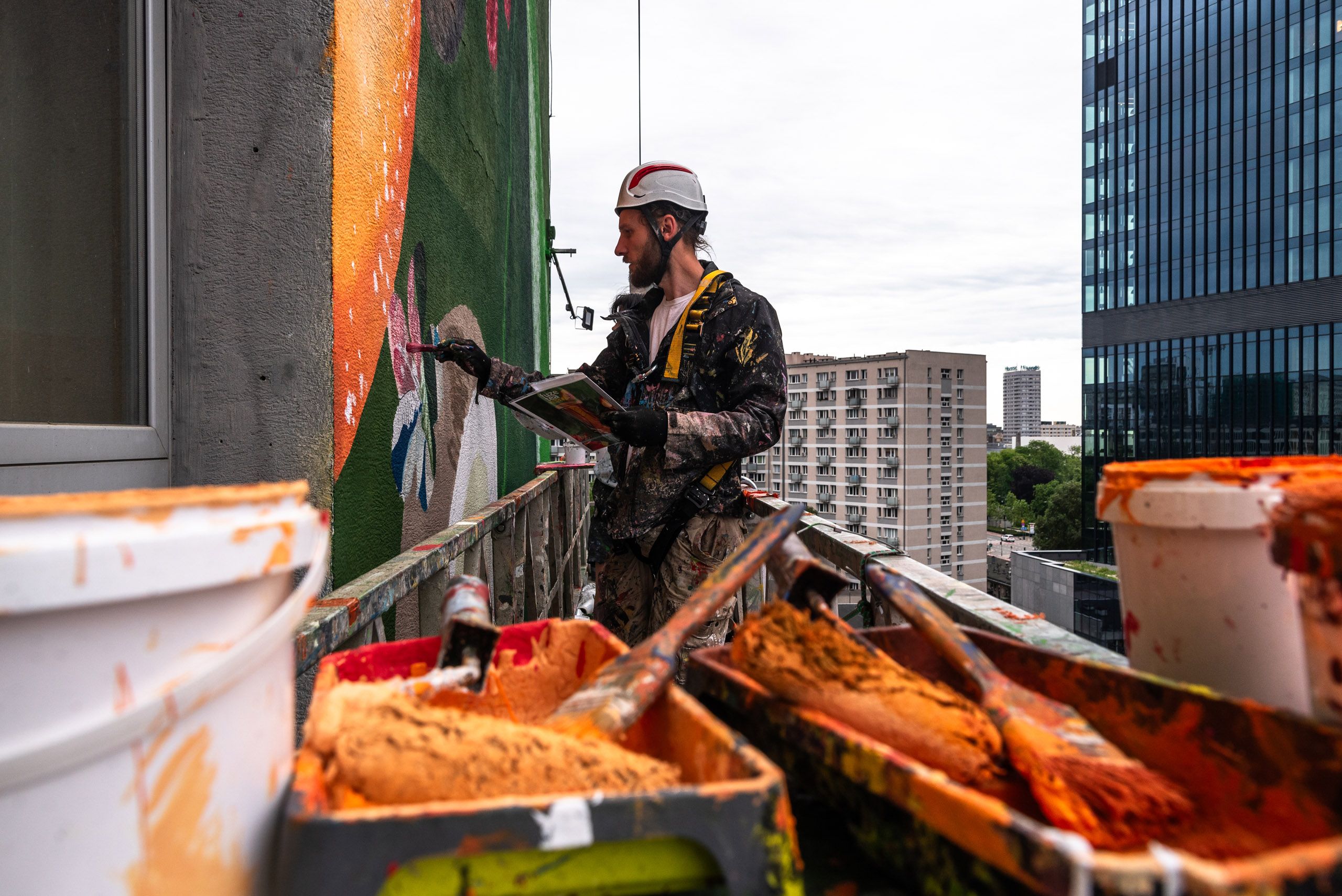 muralista malujący detale podczas kampanii dla Fuze Tea na windzie zewnętrznej
