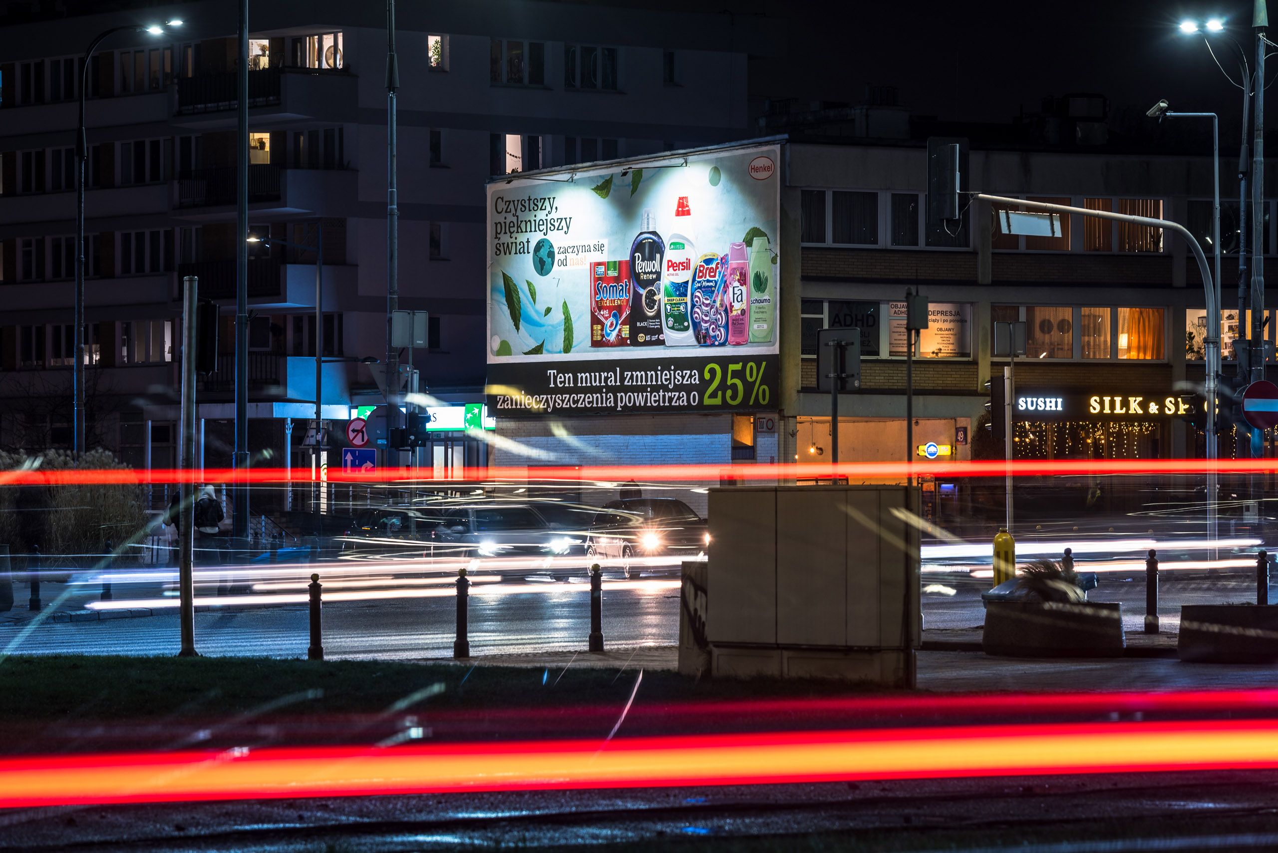 nocny widok z ruchliwego skrzyżowania na mural reklamowy dla marki Henkel przedstawiający ich produkty