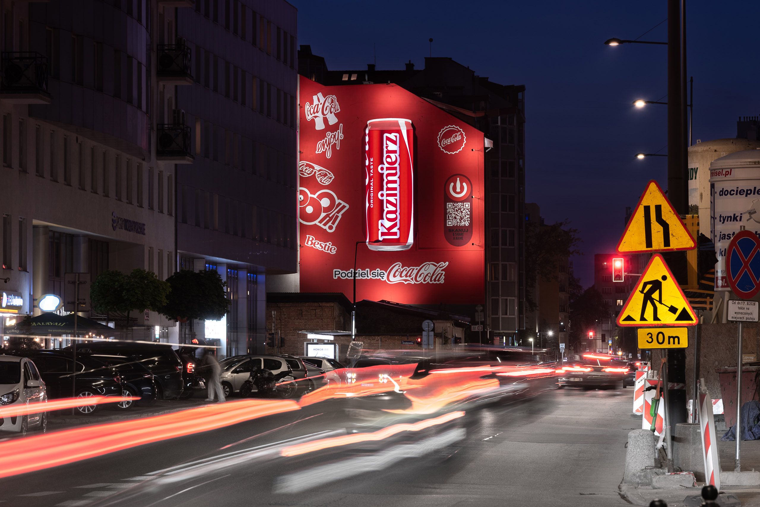 mural reklamowy w połączeniu z ekranem led dla marki Coca-Cola, na środku zdjęcia zamontowany ekran LED imituję puszkę Coca-Coli wyświetlając nazwę imienia zgodną z layoutem Coli
