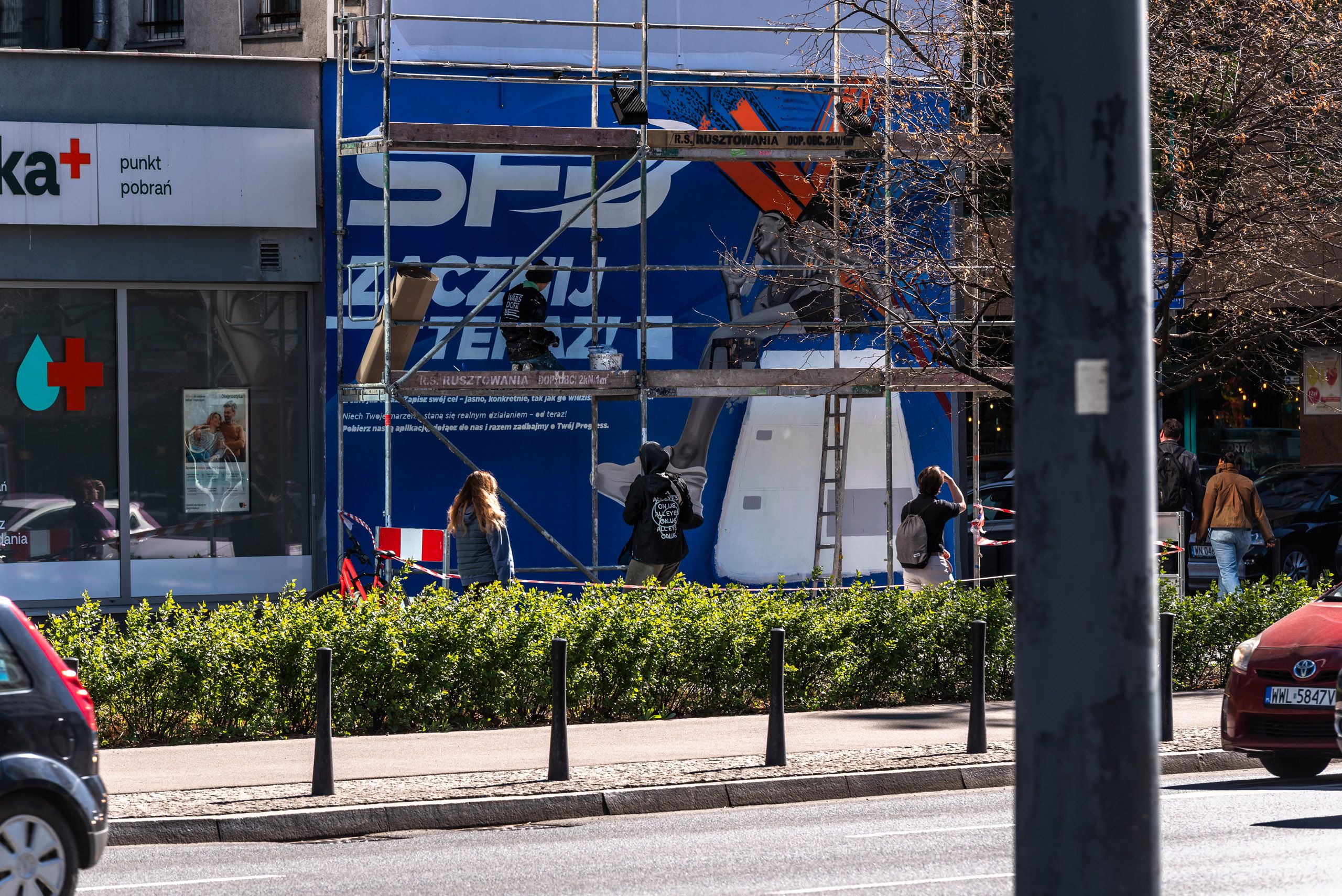 mural reklamowy dla marki SFD ujęcie podczas prac muralistów z dalszego planu