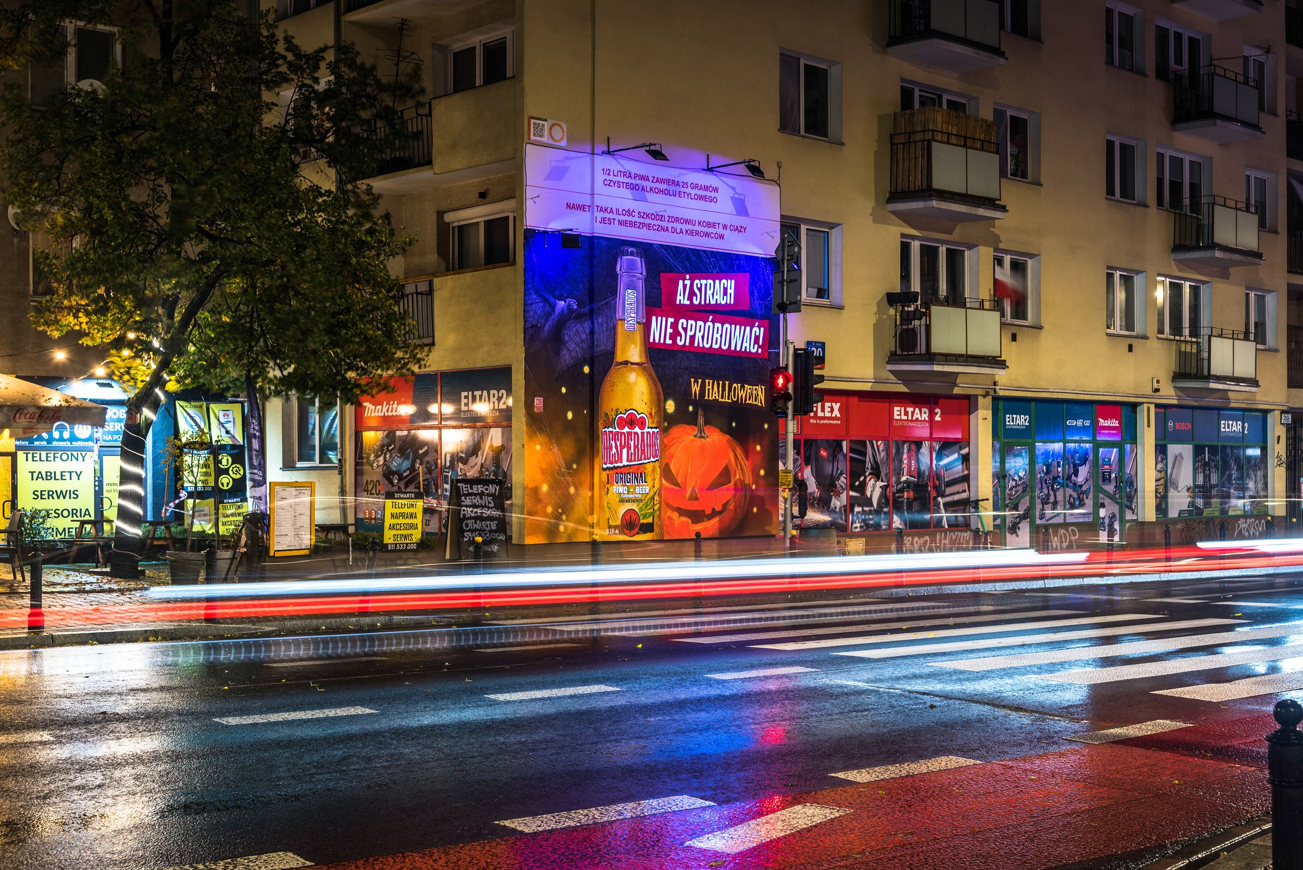 nocna ekspozycja przedstawiająca mural reklamowy dla marki Desperados z podświetlonym lampami UV padającymi na mural