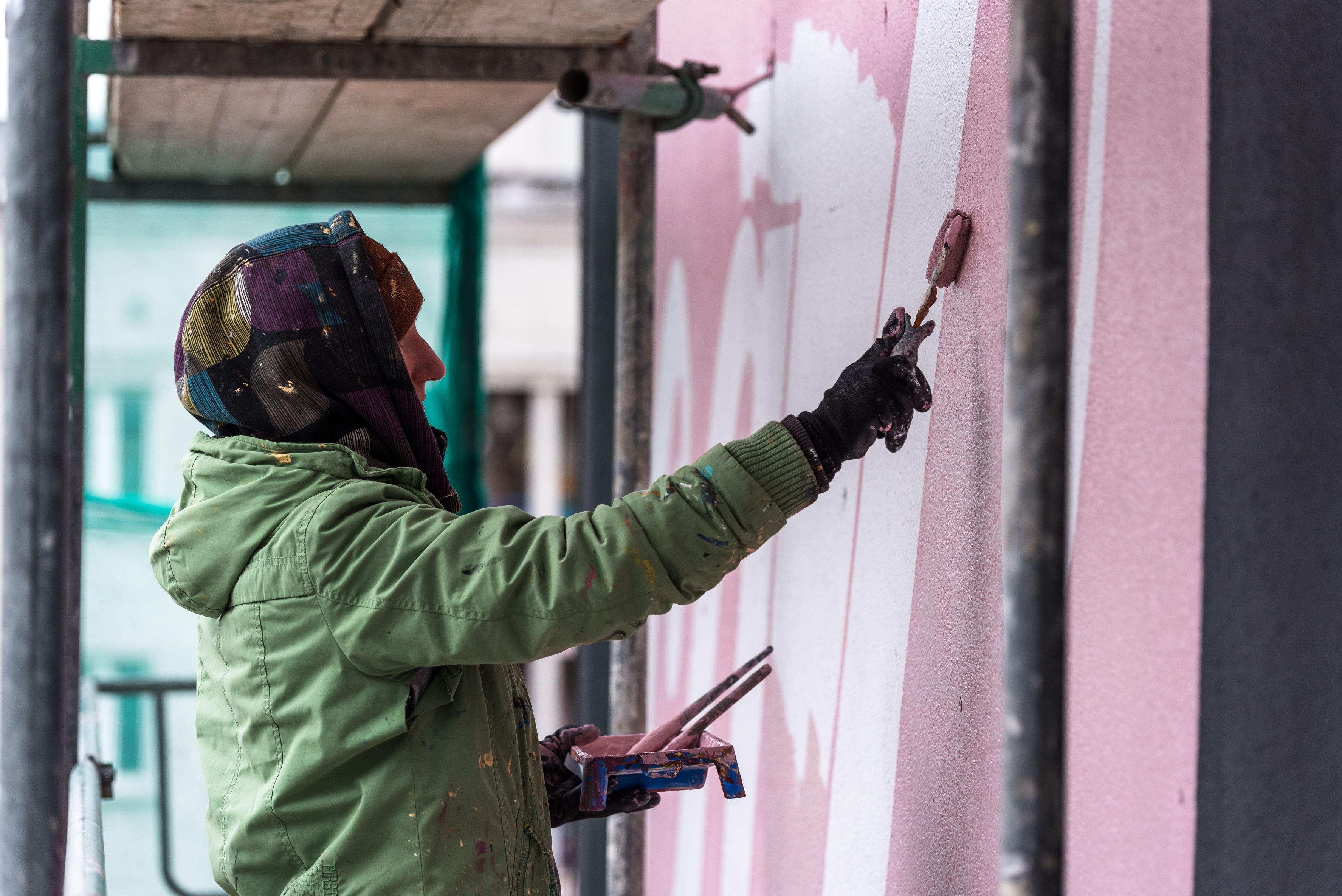 malarz trzyma pędzel i maluje mural dla coca-coli