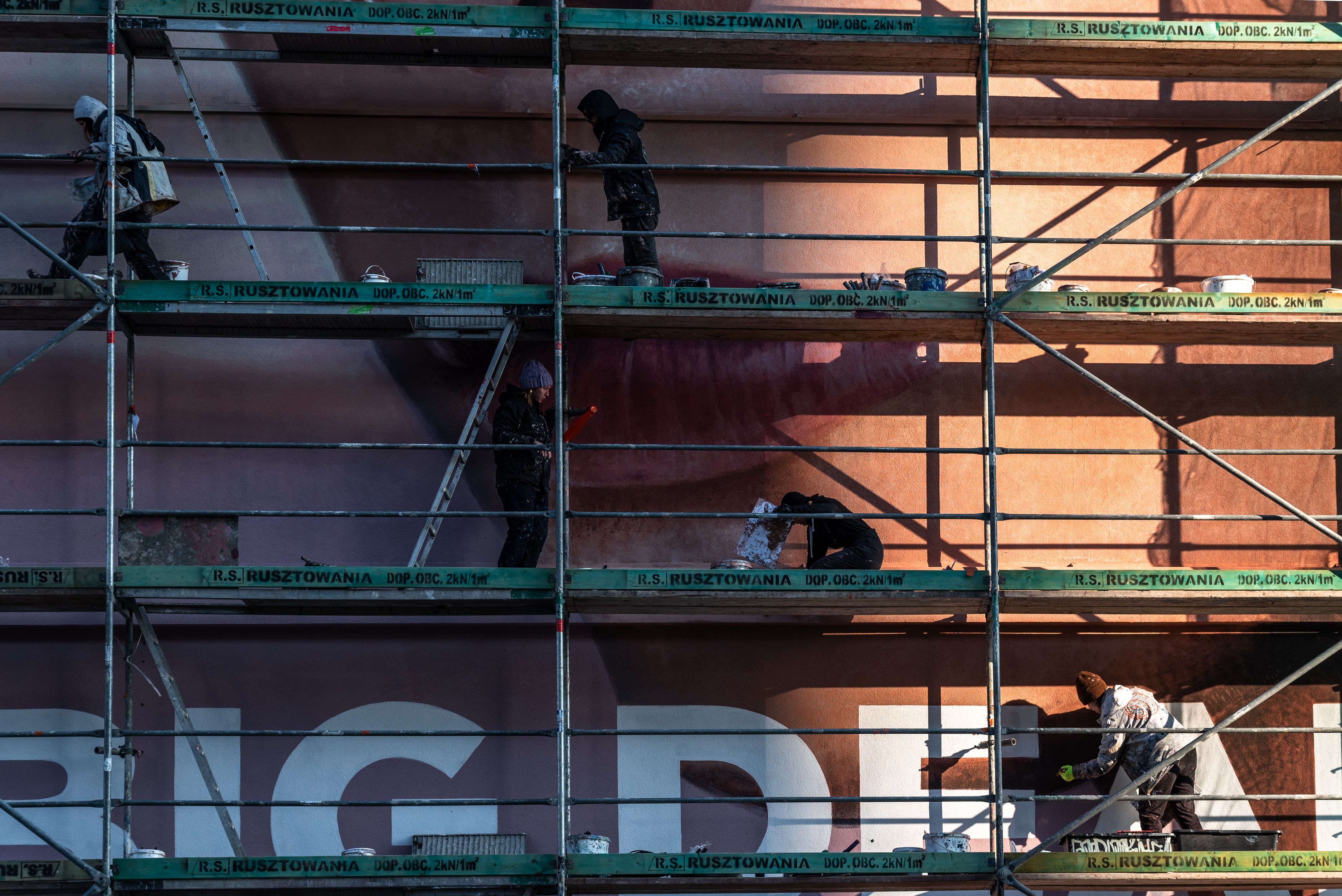 malarze na rusztowaniu podczas malowania muralu dla Loreal