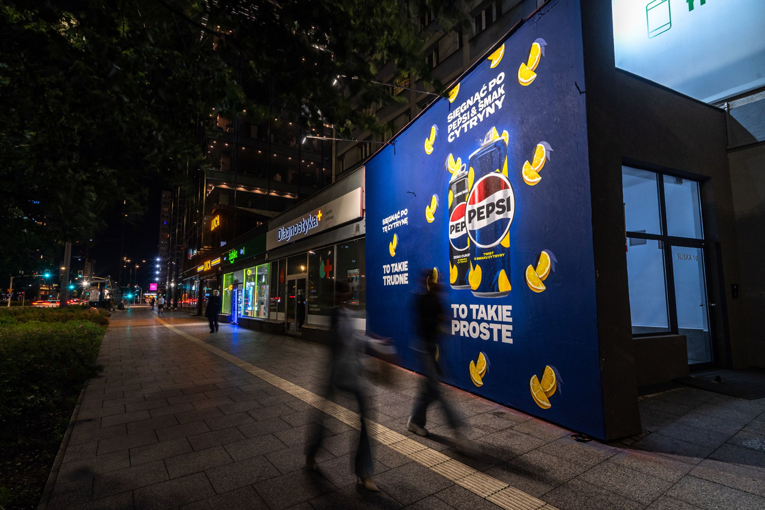 mural reklamowy dla marki Pepsi przedstawiający produkt - 2 puszki Pepsi Twist na niebieskim tle z cytrynami